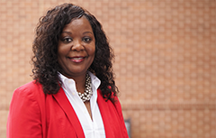 Female wearing red blazer in in front of brick wall 